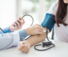 Doctor,using,sphygmomanometer,with,stethoscope,checking,blood,pressure,to,a